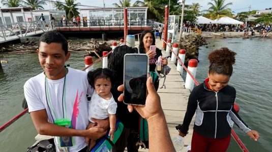 migrantes con sus celulares en Necoclí (Colombia).