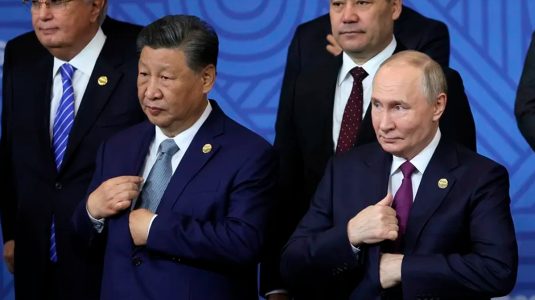 El presidente ruso Vladimir Putin (d) habla con el presidente chino Xi Jinping (2-i)