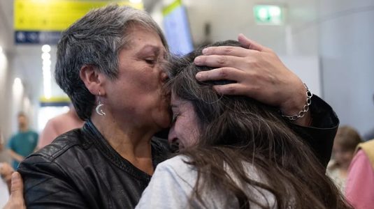 Claudia Díaz (i) y su hermana Natalie a su llegada al Aeropuerto Internacional Arturo Merino Benitez en Santiago de Chile.